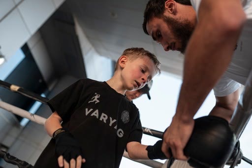 Illias wrapping a young student's hands before training